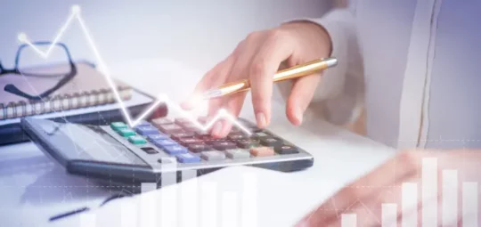 Persona usando una calculadora con superposición de gráficos de crecimiento financiero.